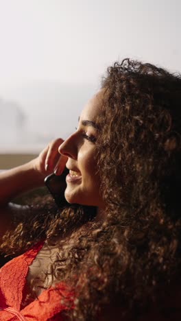 woman with curly hair talking on the phone