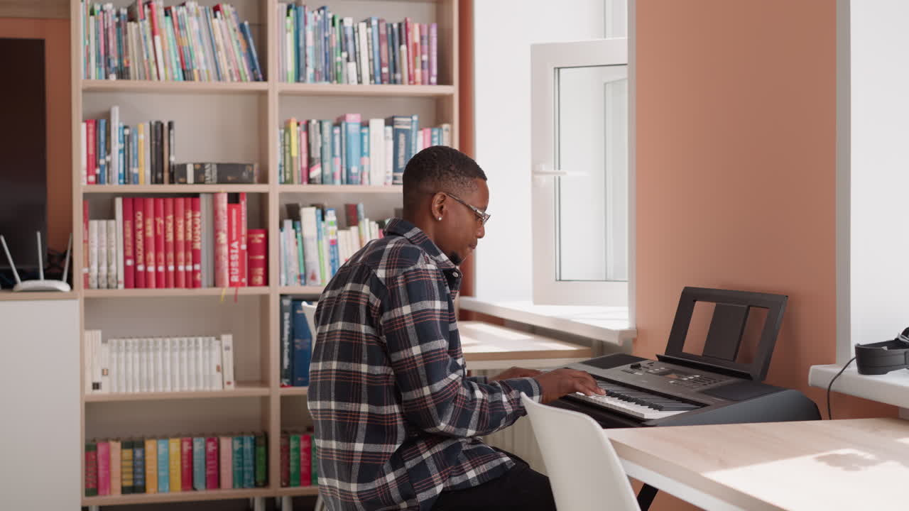 Black man engages in digital piano play. African American musician practices music on synthesizer keyboard dreaming about big stage. Playing in residence