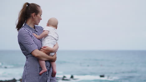 a captivating portrait captures a mother tenderly kissing her daughter against the backdrop of the sea and beach. a joyous family enjoys their vacation, and the mom embraces her toddler