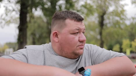 closeup of face of concentrated overweight man standing by horizontal bar outdoors closeup of face of concentrated overweight man standing by horizontal bar outdoors a break during training struggle with excess weight