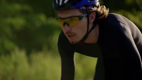 cyclist in helmet rides bicycle along the track, gaining speed, close up