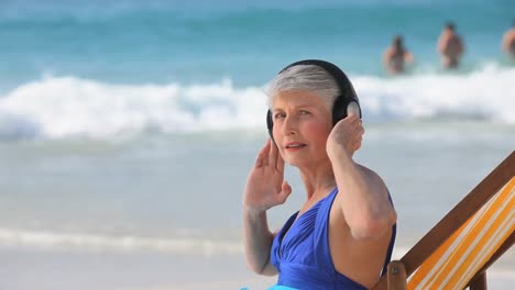 Ältere-Frau,-Die-Am-Strand-Musik-Hört