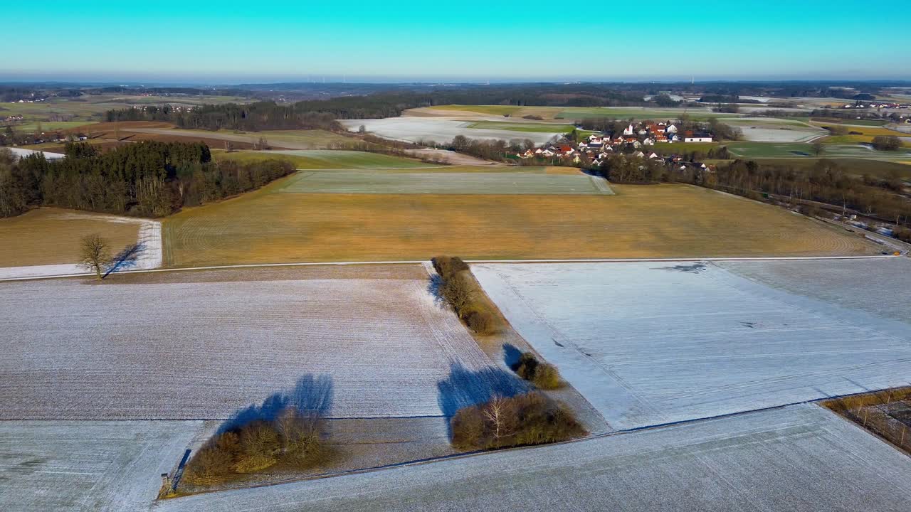 Solbelyste rimfrosne jorder med landsby i det fjerne