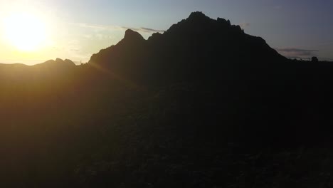 passing over the roof of a house as the sun peeks over the dark mountains