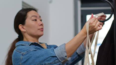 woman returning from shopping hanging up coat on stand before carrying bag into home