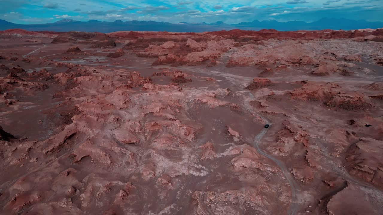 Description: Forward drone aerial of Valle de la Luna's Mars-like landscape, San Pedro de Atacama, Chile with red rock formations and dramatic desert terrain
