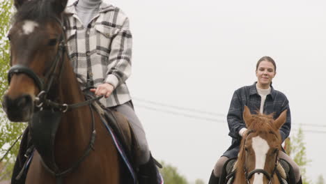 twee mensen die bruine paarden berijden