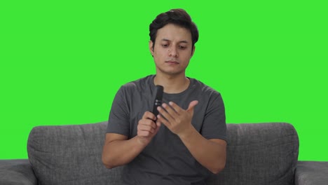 indian man trying to fix tv remote green screen