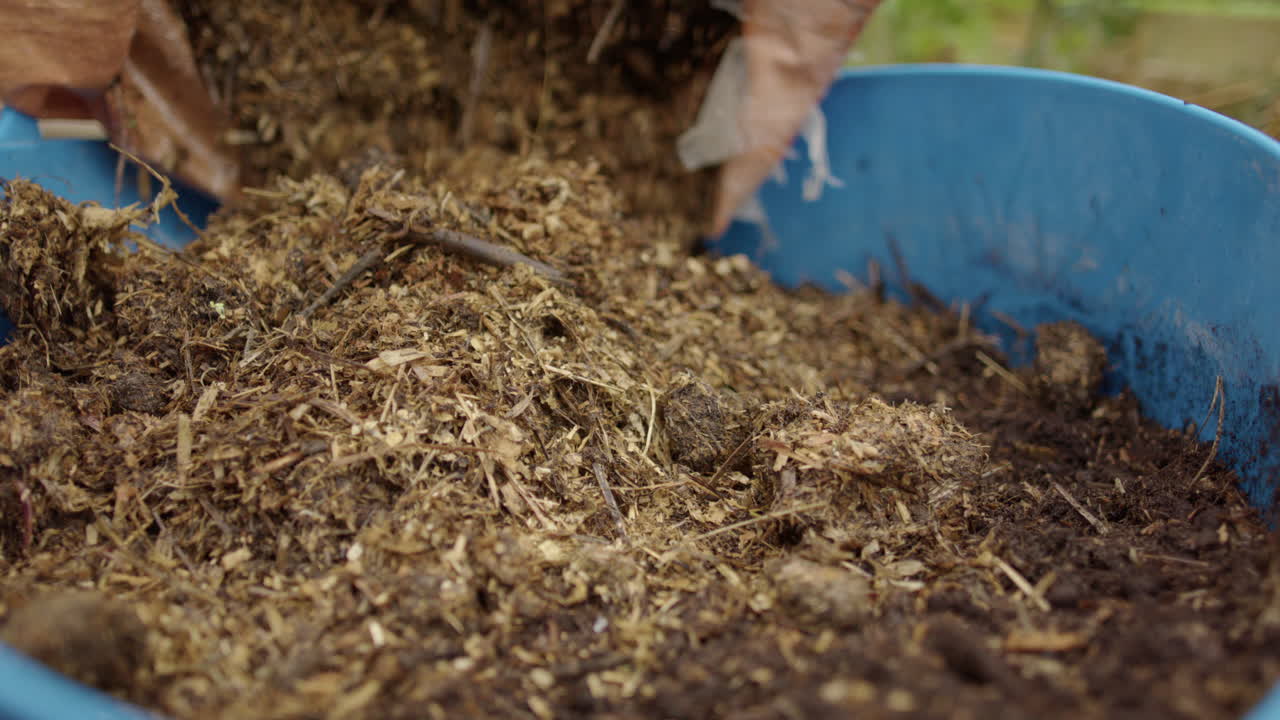 autosostenibilidad: el abono herboso se vierte de una bolsa a un balde