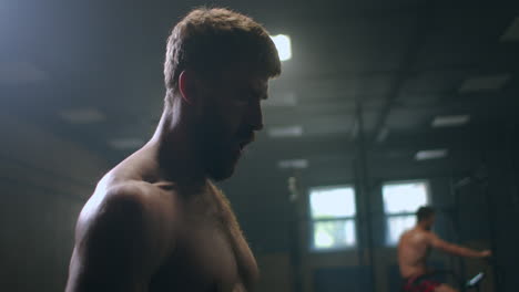 time to rest. young athletic man in sportswear looking exhausted while standing in front of windows at gym.