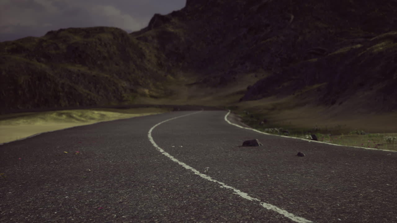 Winding road through mountainous terrain under a dusky sky at twilight