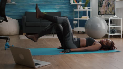 slim black woman doing bycle exercise sitting on yoga map