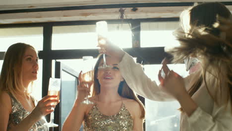 Three-Young-Women-In-Party-Dresses-Toasting-With-Champagne