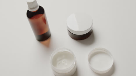 close up of cream tubs and glass bottle with copy space on white background