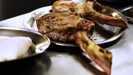 Close-Up-View-of-Two-Juicy-Tomahawk-Steaks-on-a-Silver-Plate