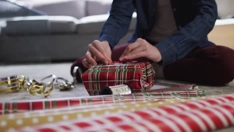 sección media de la mujer envolviendo regalos de navidad en casa