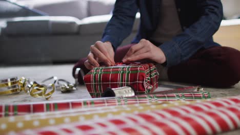 mittlerer abschnitt einer frau, die weihnachtsgeschenke zu hause einpackt