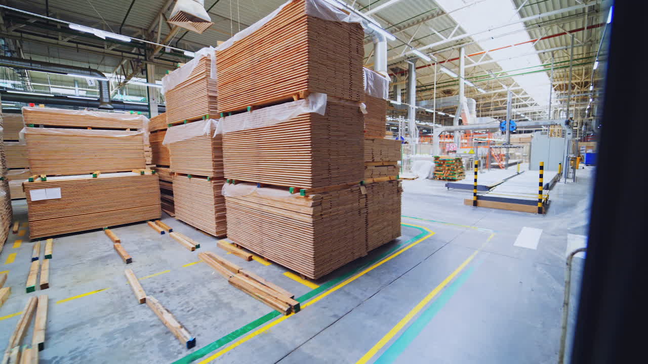 Large warehouse of timber materials. Motion camera inside the warehouse. Neatly stacked wooden boards for floor production in a warehouse.
