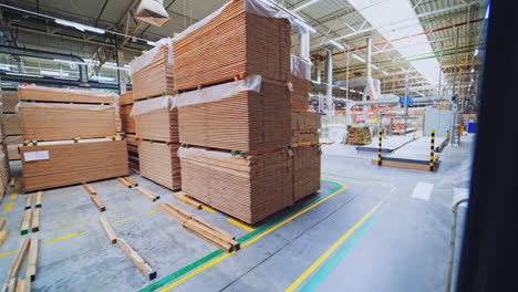 large warehouse of timber materials. motion camera inside the warehouse. neatly stacked wooden boards for floor production in a warehouse.