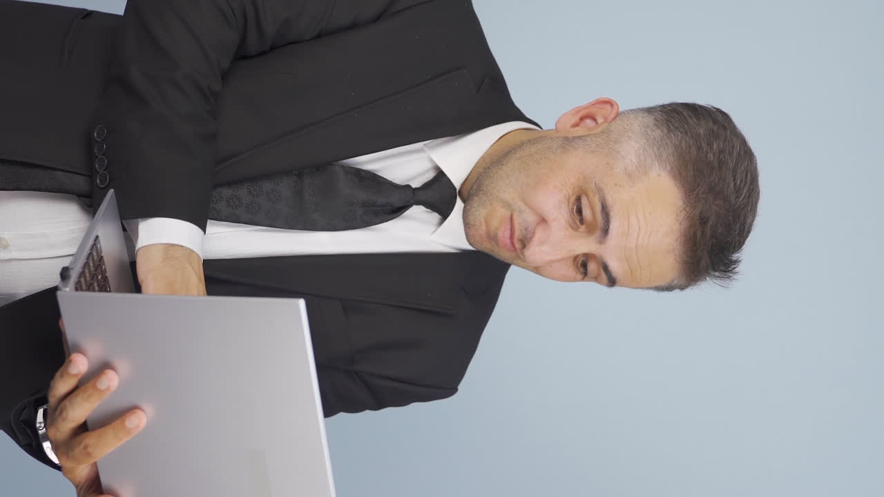 만족한 사업가의 수직 비디오는 노트북을 보고 승인합니다.