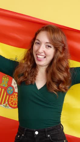 happy redhead woman wrapped in spanish flag
