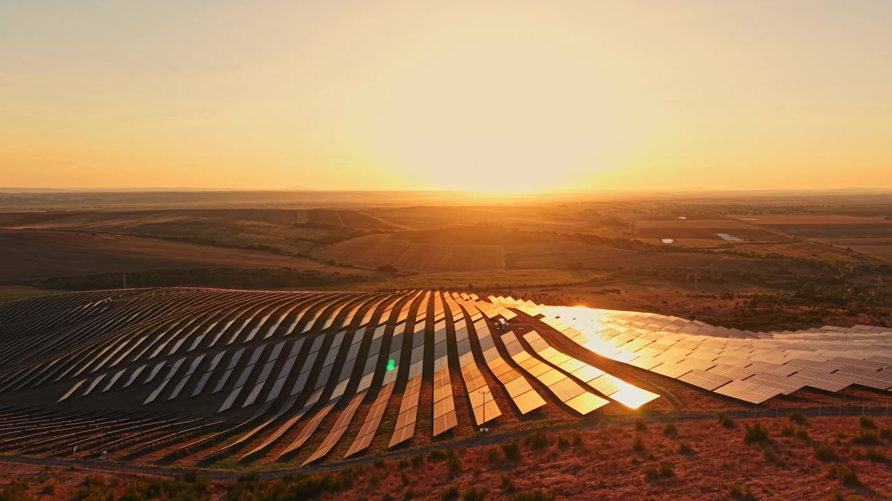 Solnedgang over en solcellepark i et landområde, der fremhæver vedvarende energi og arealanvendelse