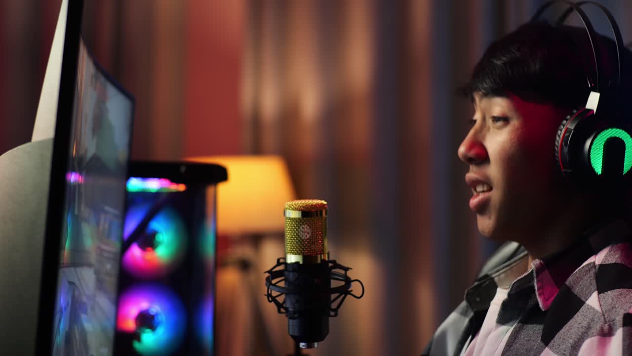 Close Up Side View Of Asian Boy Streamer Playing Game Over Network On Personal Computer. Challenge And Bully Threat Killing Competitor, Live Stream Video Game, Desk Illuminated By Rgb Led Strip Light