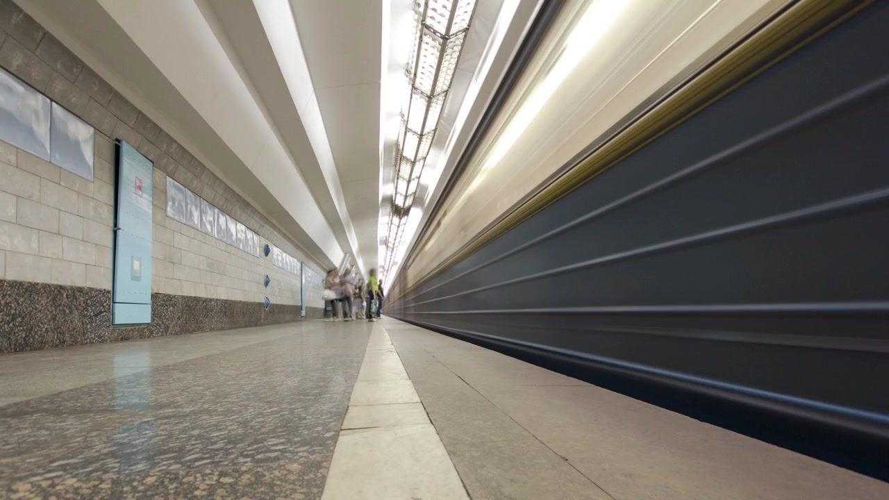 Un tren subterráneo saliendo de la estación de metro Derzhprom en la Línea Oleksievska del metro de Járkov en timelapse hyperlapse, con pasajeros en un andén, en Járkov, Ucrania