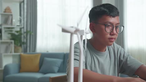 teenager studying with wind turbine models