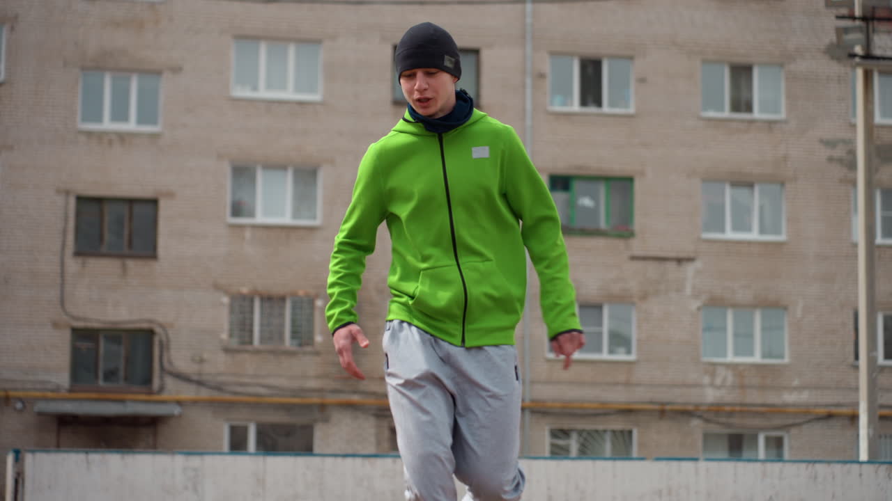 fútbol callejero de estilo libre, atleta practicando fútbol de estilo libre cerca de edificios de apartamentos mientras corre, práctica de fútbol urbano dinámico mostrando habilidades individuales de control del balón cerca de bloques residenciales