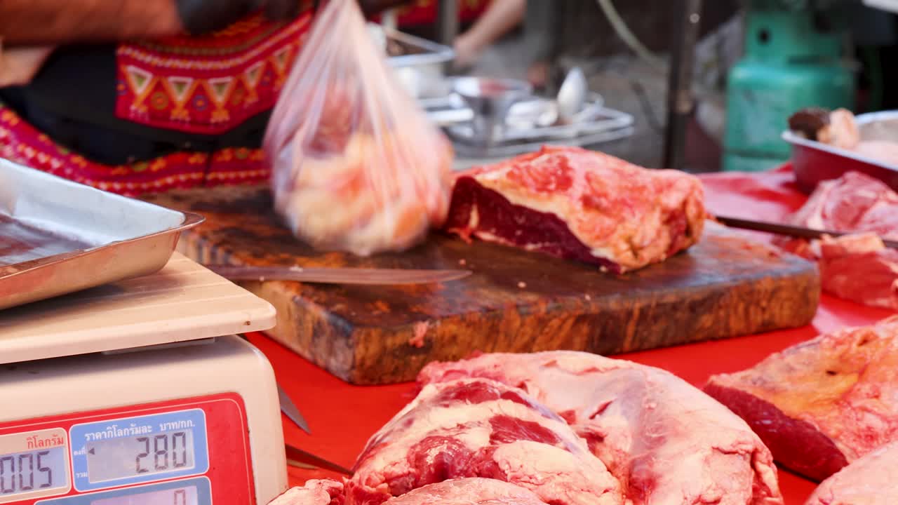 Butcher wearing gloves weighs and bags raw beef at outdoor market, natural daylight, close-up view