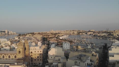 Drone-shot-of-skyscrapers-buildings-and-a-marina-in-the-distance-during-sunset