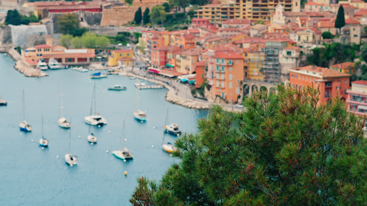 View of the colourful buildings of Villefranche sur Mer, France on the coast with small boats docked on the sea