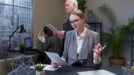 Displeased-upset-young-businesswoman-accountant-reading-documents,-analyzing-financial-papers-data