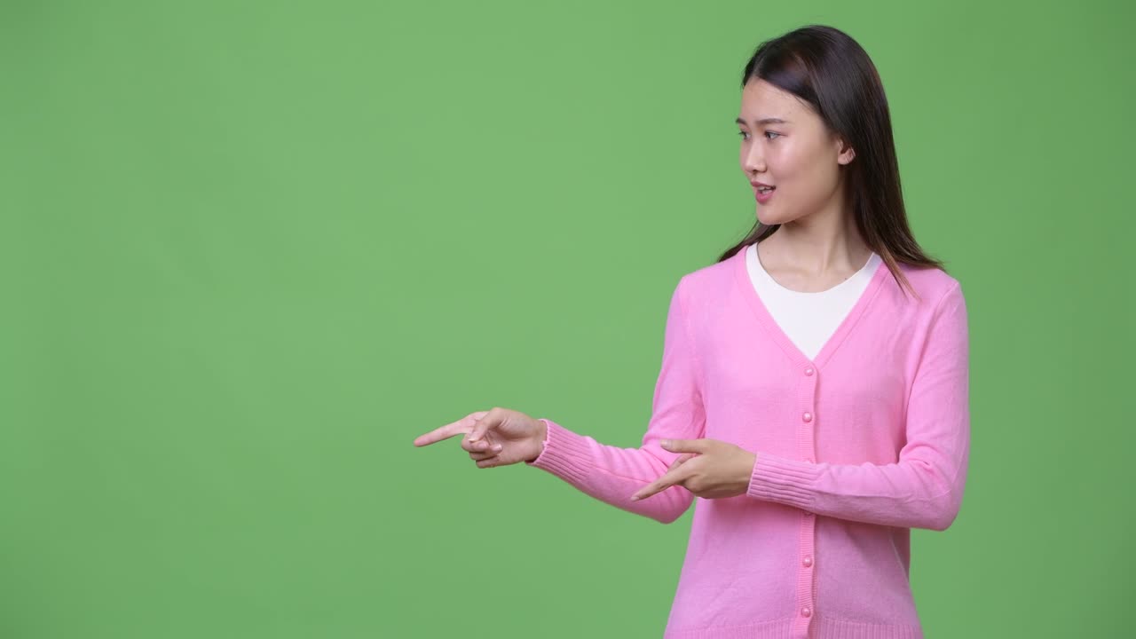 Young beautiful Asian woman showing something