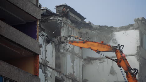 destruction of the premises ruined by an earthquake. demolishing equipment is breaking the upper floors. dusty cloyds rise in the air.