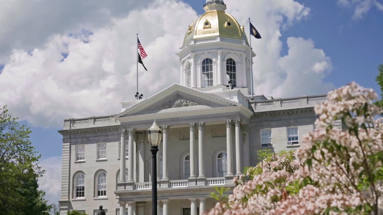 Filmisk panorering og tilt fra farverige blomster i forgrunden til det historiske New Hampshire State House i Concord, New Hampshire på en smuk sommerdag