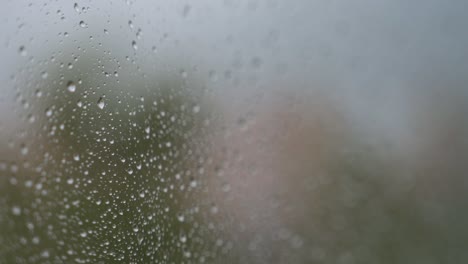 Vista-De-Enfoque-Estrecho-De-Vidrio-Lluvioso-Mientras-Se-Ven-Gotas-De-Lluvia-En-Una-Ventana-Durante-El-Tiempo-Sombrío-Y-Nublado