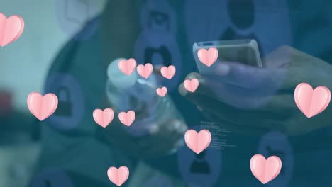 animation of digital icons and pink hearts floating over mid section of man using smartphone