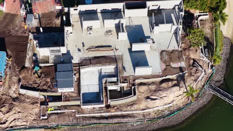 drone footage captures construction progress on a luxury house by a canal in gold coast, australia, under bright daylight