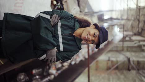 portrait of a young african-american woman checks a conveyor belt at a recycling plant. pollution control