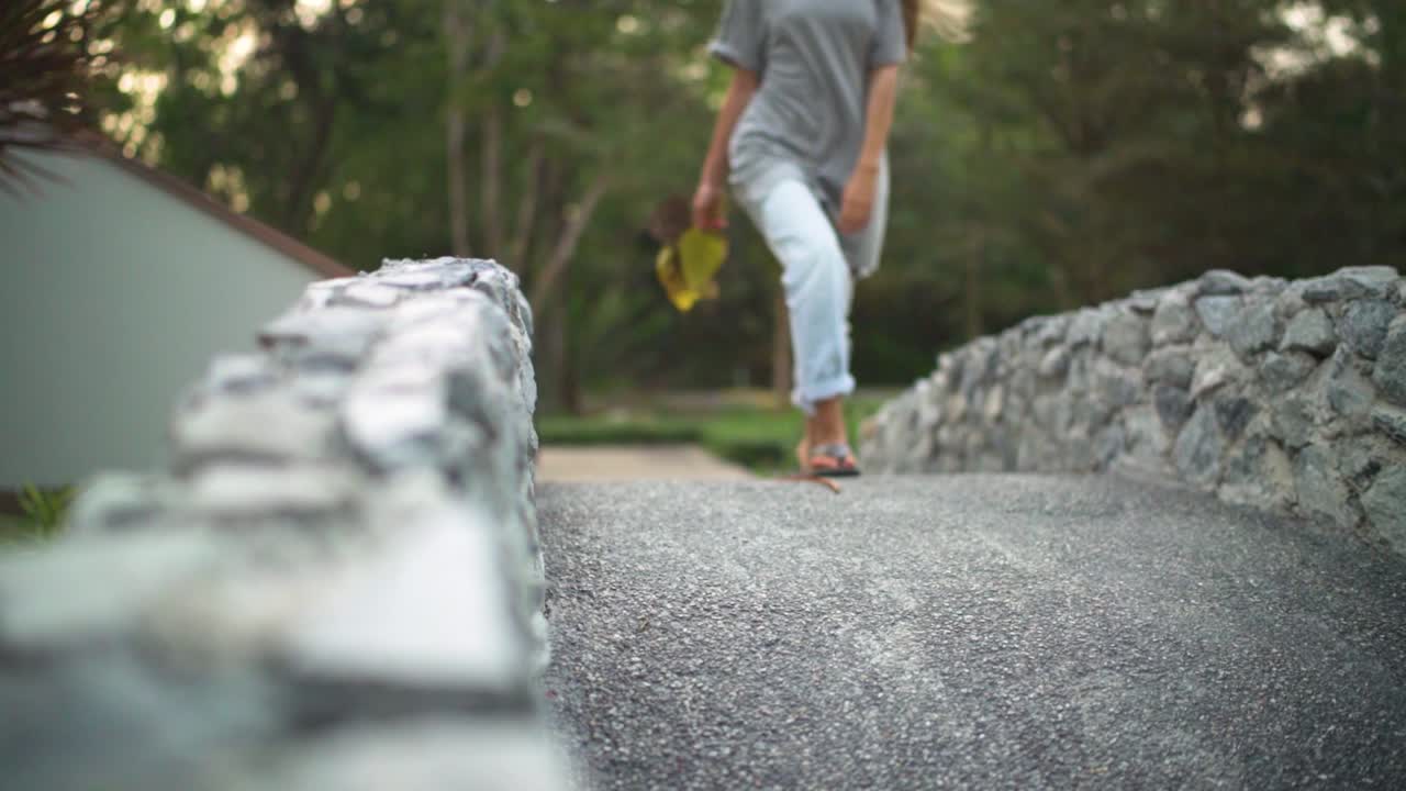 카메라를 향해 화창한 날에 다리 위를 걷는 젊은 여성