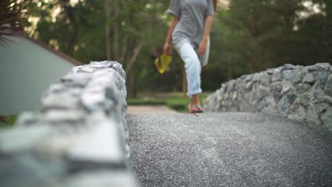 young female walking over a bridge on a sunny day towards camera