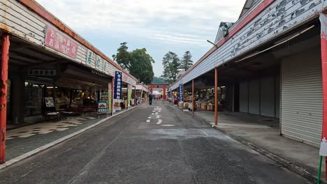 walking along the main road facing a big torii gate and shoops at yutoku inari shrine in kyushu, japan