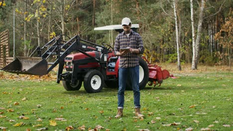 farmer using tablet near tractor in autumn field