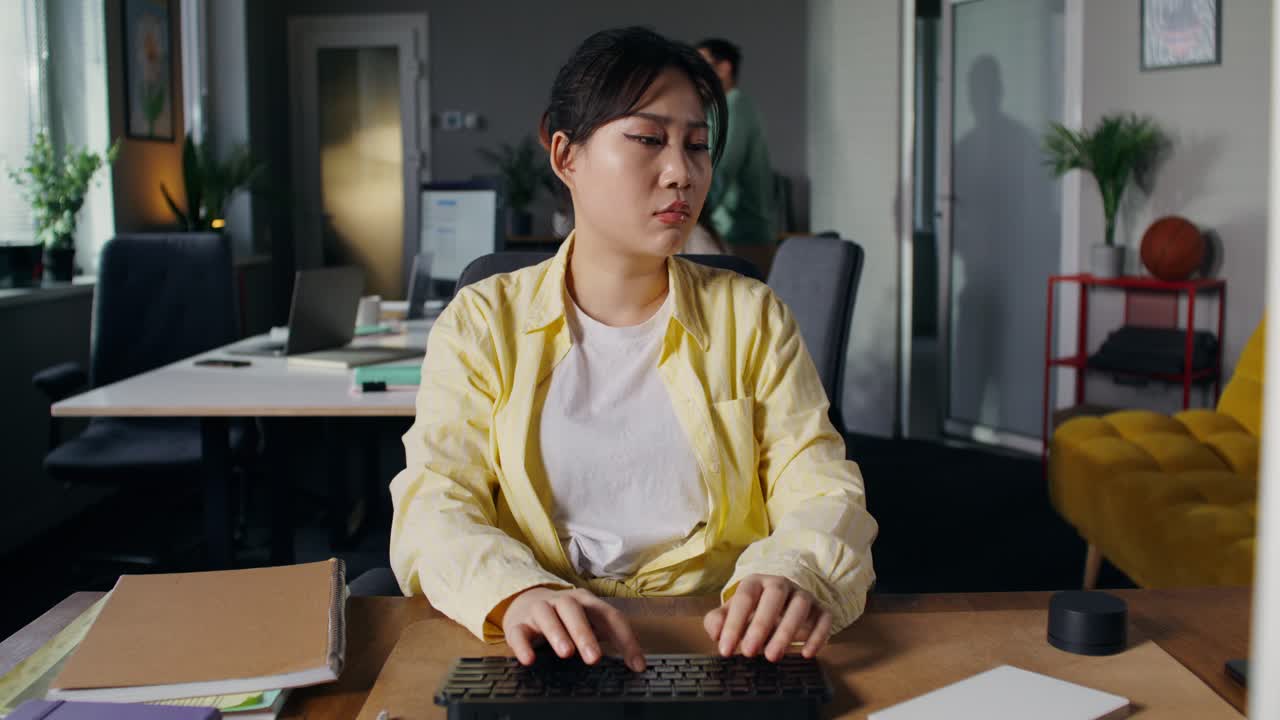 Woman Working at a Desk in a Busy Office