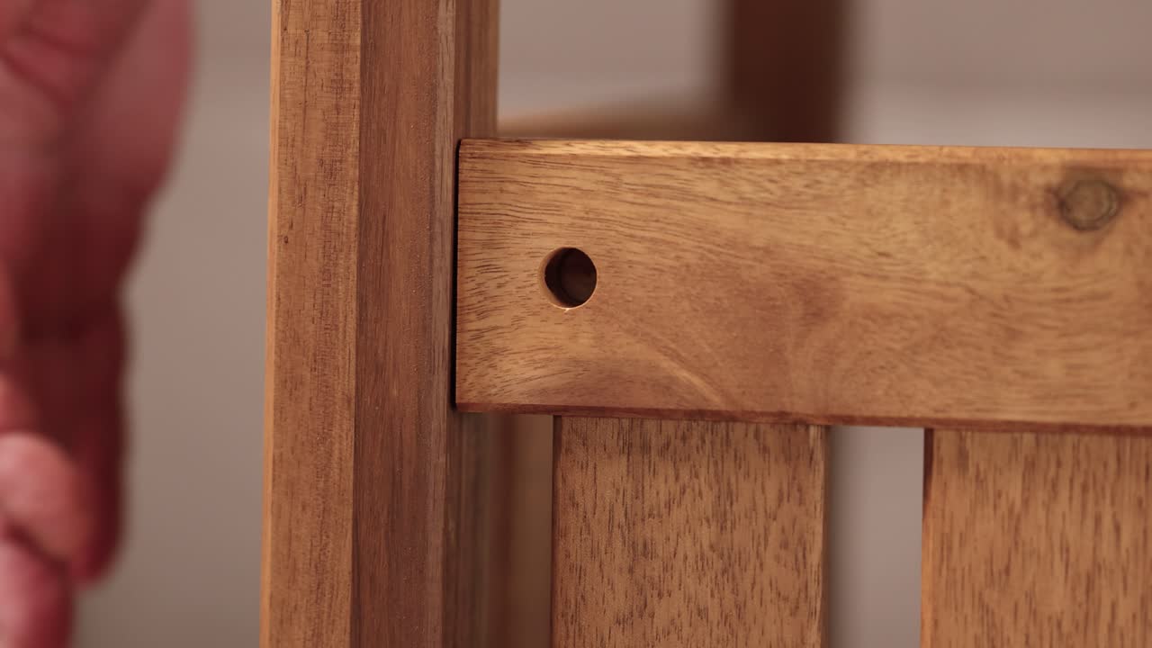 Hands carefully align wooden pieces for furniture assembly in a softly lit environment, emphasizing craftsmanship and attention to detail