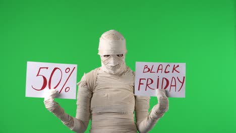 mummy holding black friday and 50% off sale signs on a green screen