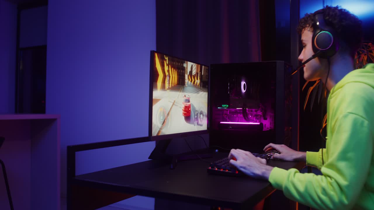 Gamer playing video game on computer with neon lighting