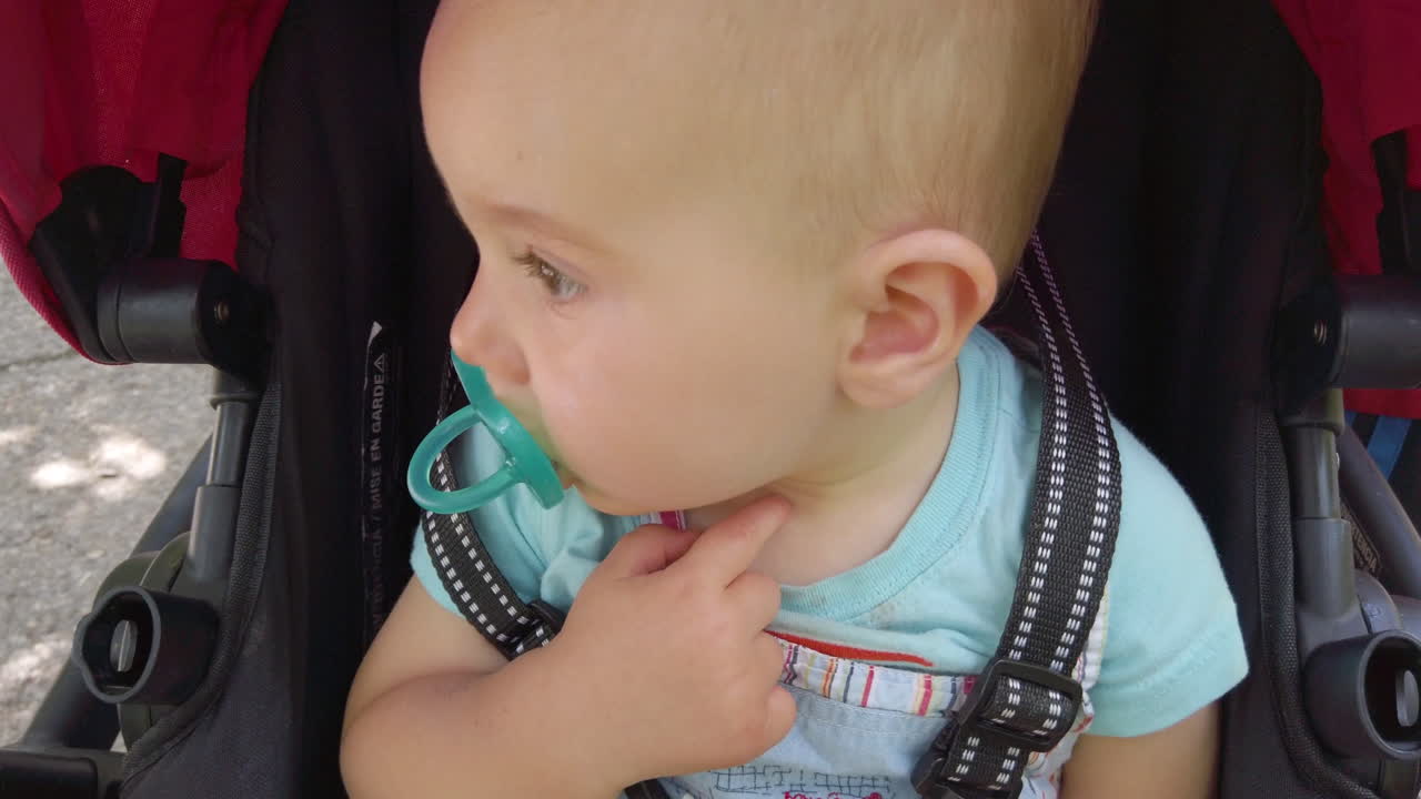Baby boy riding in a stroller while sucking on a pacifier